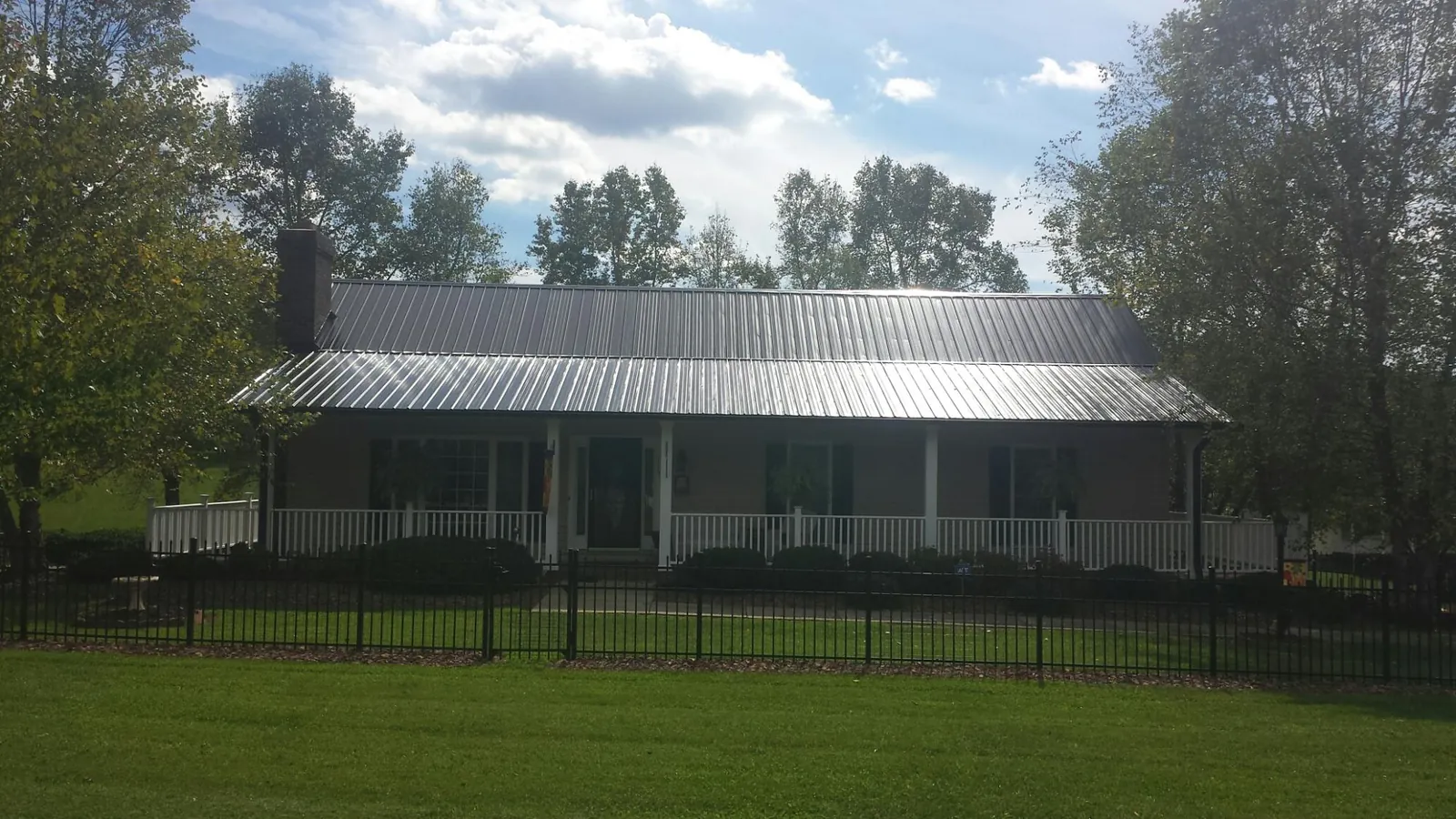 Gray metal roof on a brick ranch with a full width front porch — Gutter Guard Installation work by our crew in Lisbon