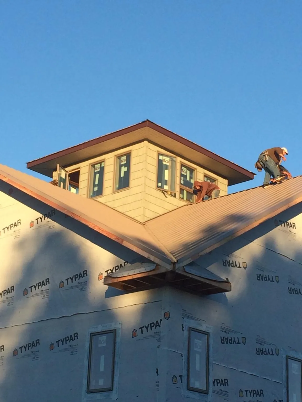 Roofers working around a rooftop cupola on a new metal roof at sunset — Roof Waterproofing in Lisbon by Roofing Brothers